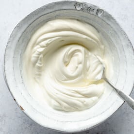sour cream and greek yogurt mixed together in a bowl with a metal spoon