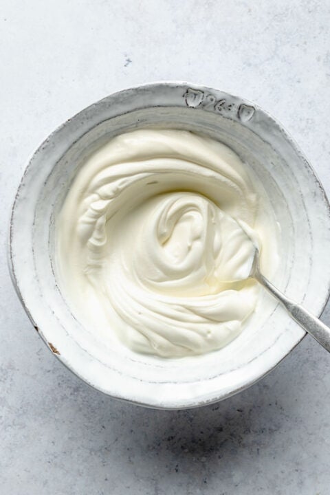 sour cream and greek yogurt mixed together in a bowl with a metal spoon