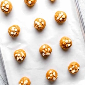 white chocolate and macadamia nut cookie dough balls on a parchment lined baking sheet