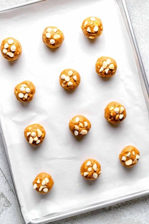 white chocolate and macadamia nut cookie dough balls on a parchment lined baking sheet