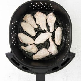 chicken wings in the basket of an air fryer tossed in flour