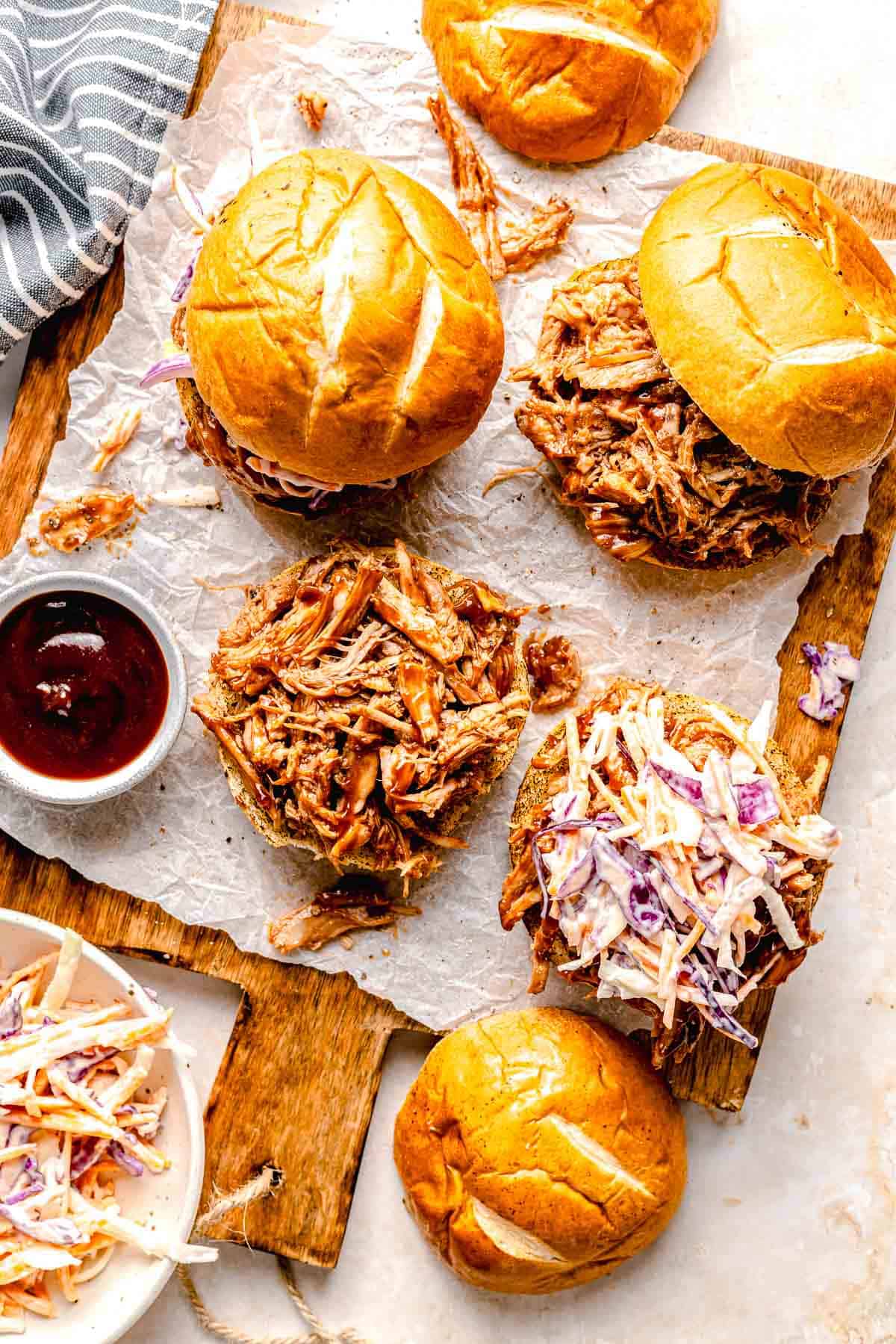 Overhead image of BBQ pork sliders on a serving board. One is open so you can see the pulled pork inside.