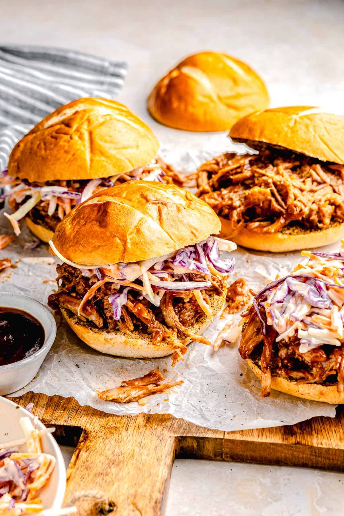 A board full of BBQ pulled pork sliders topped with slaw.