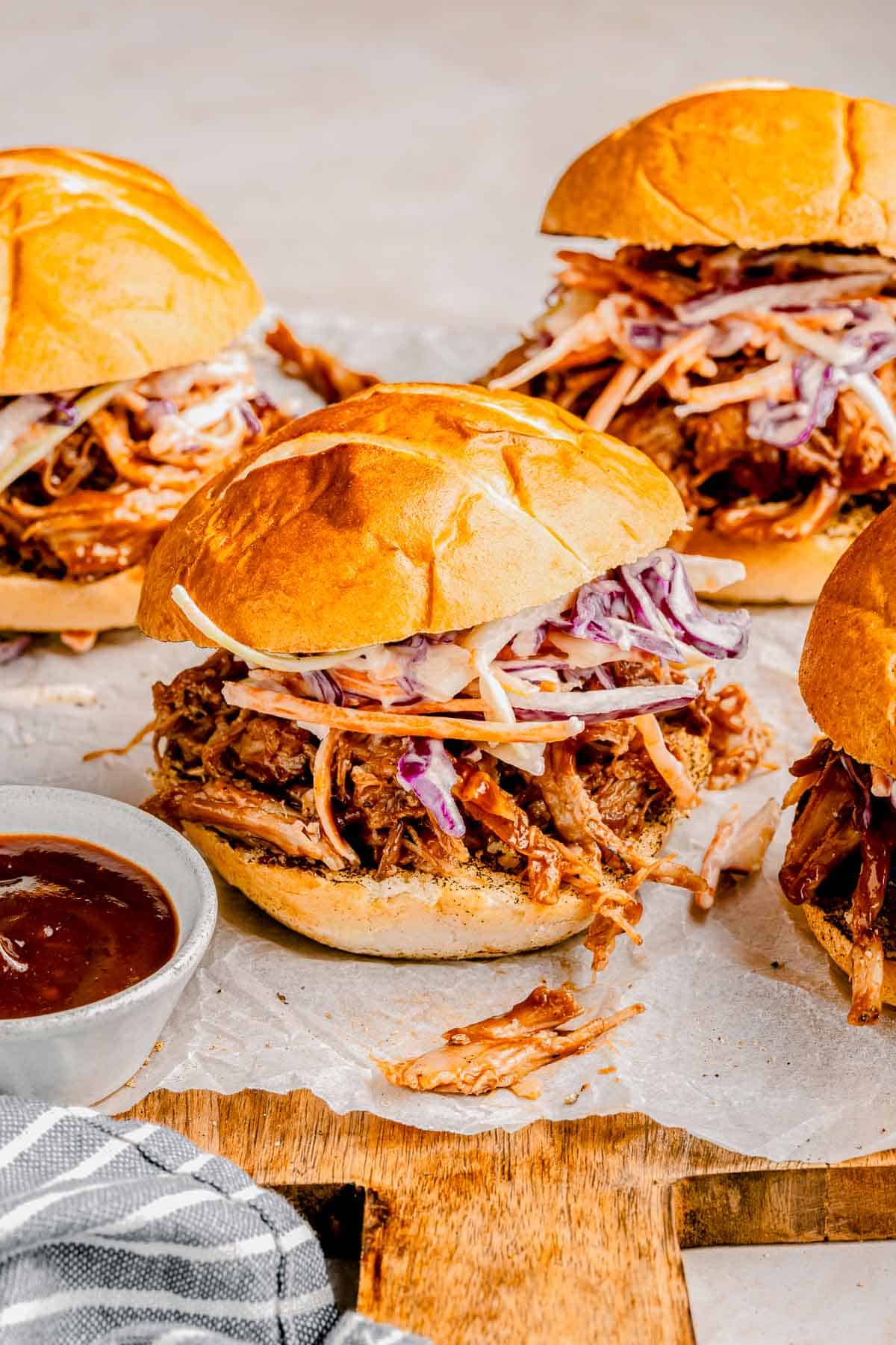 BBQ pulled pork sliders with a side of BBQ sauce.