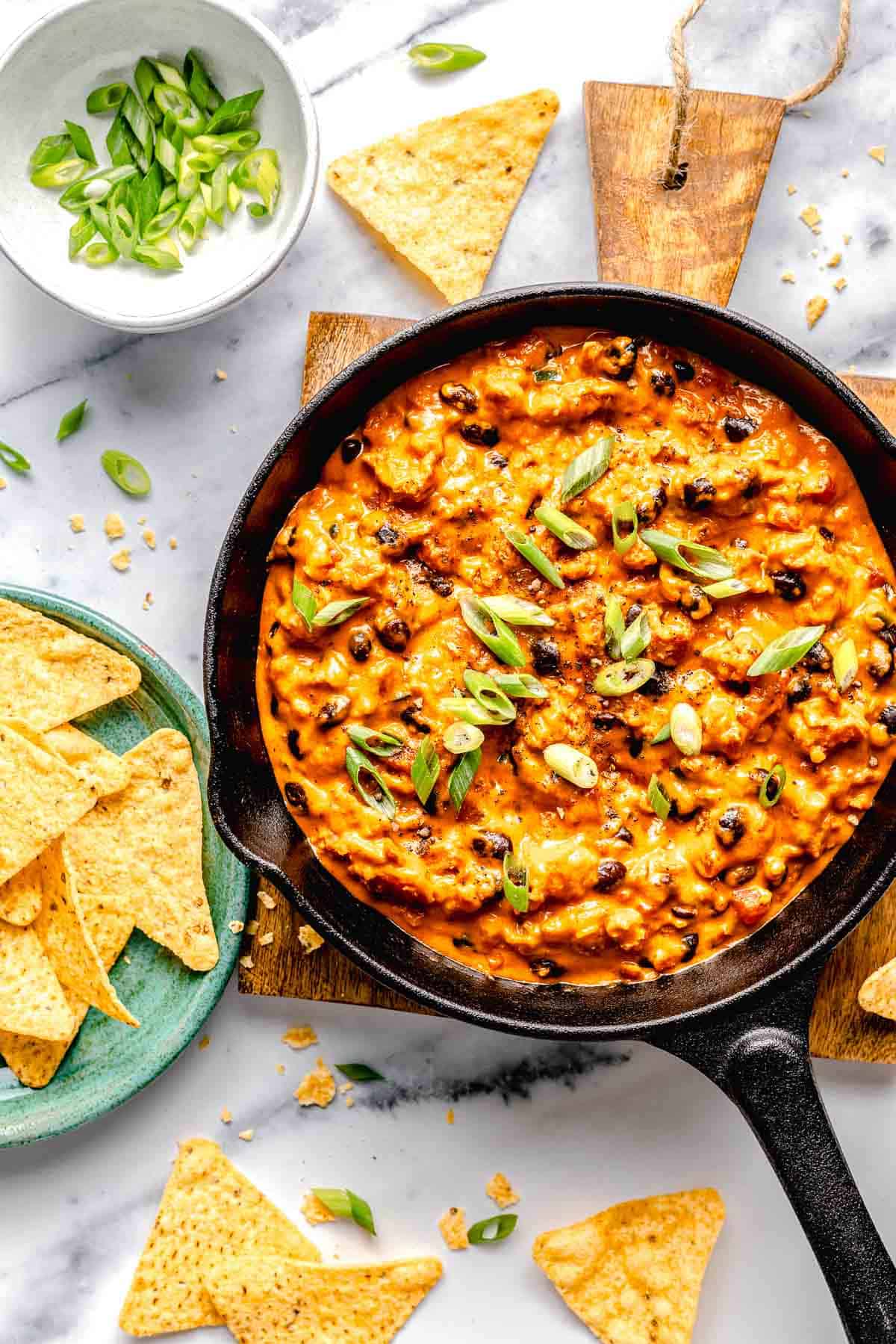 Overhead image of chili cheese dip in a skillet surrounded by tortilla chips.