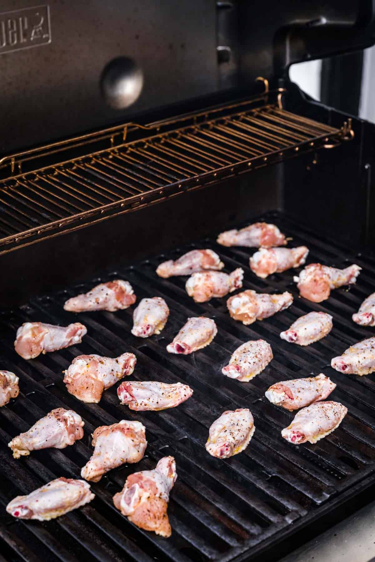 raw chicken wings evenly spaced on out a grill