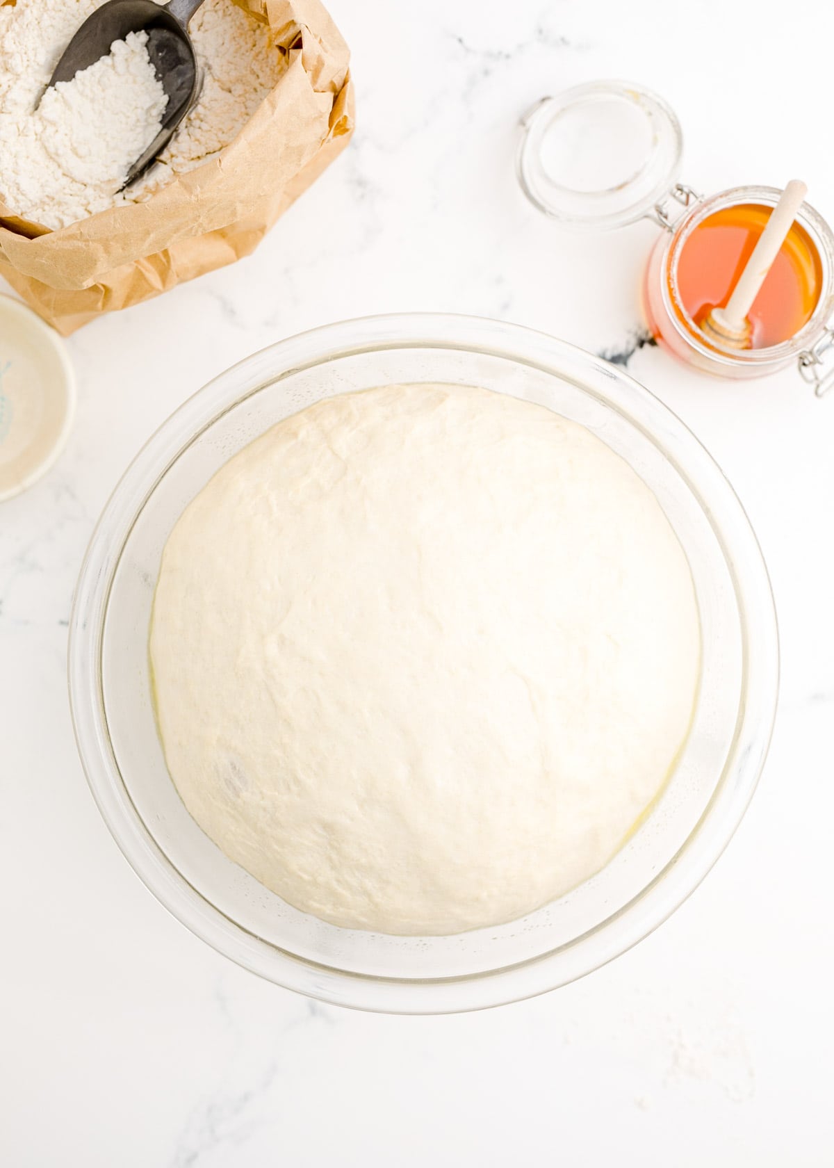 bagel dough risen double its size in a clear bowl