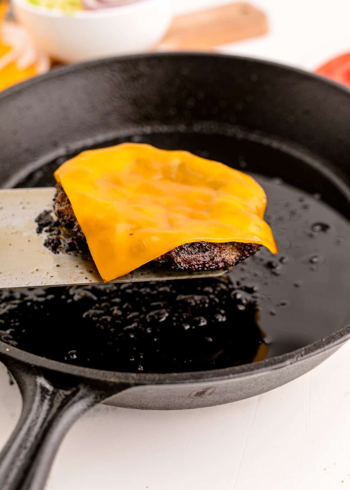 a slice of cheese melted on top of a ground beef patty
