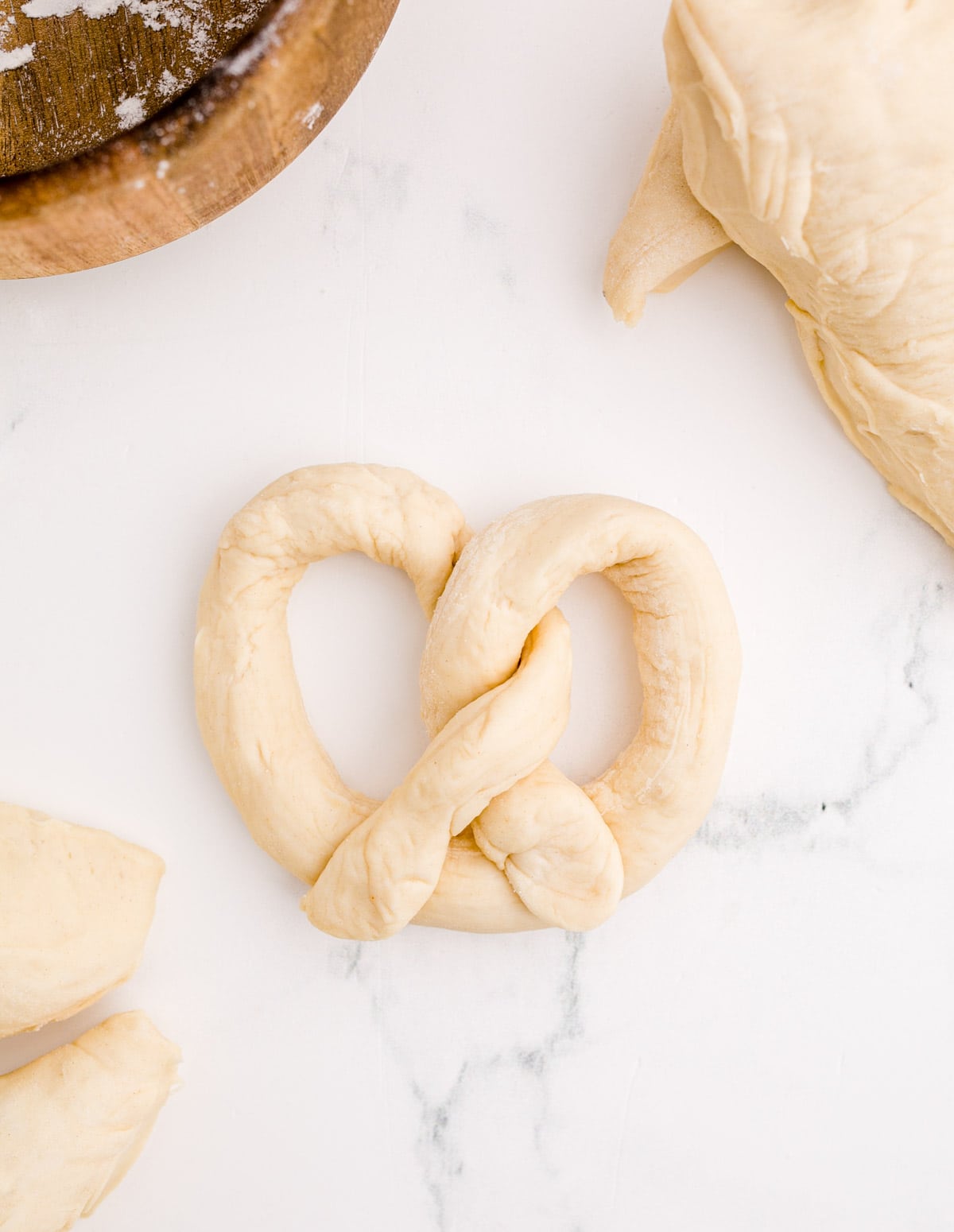 uncooked pretzel dough on a marble surface