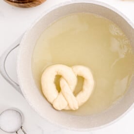 uncooked pretzel in the baking soda water in the pot