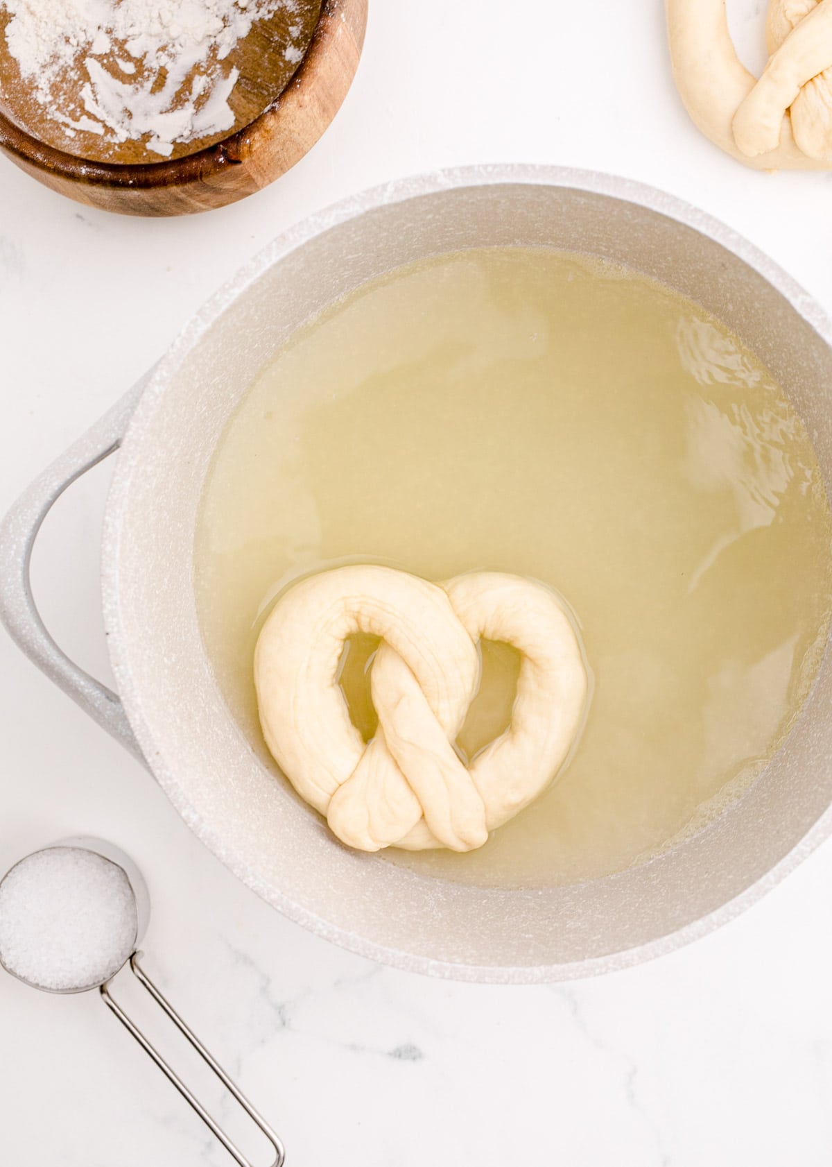 uncooked pretzel in the baking soda water in the pot