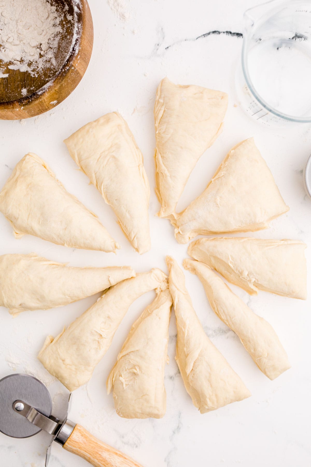 10 dough triangles separated on a marble surface