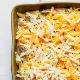 freshly shredded cheese on top of spaghetti mixture in a casserole dish