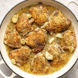 Seared chicken thighs simmer in a white wine-garlic sauce.