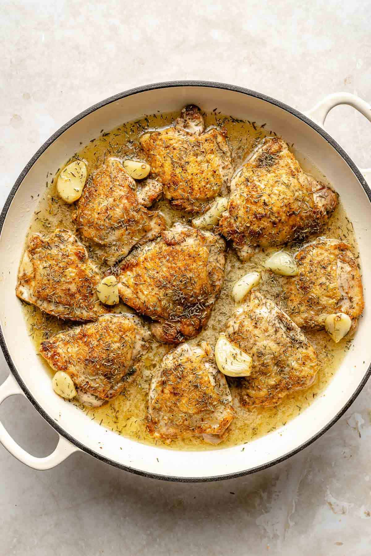 Seared chicken thighs simmer in a white wine-garlic sauce.