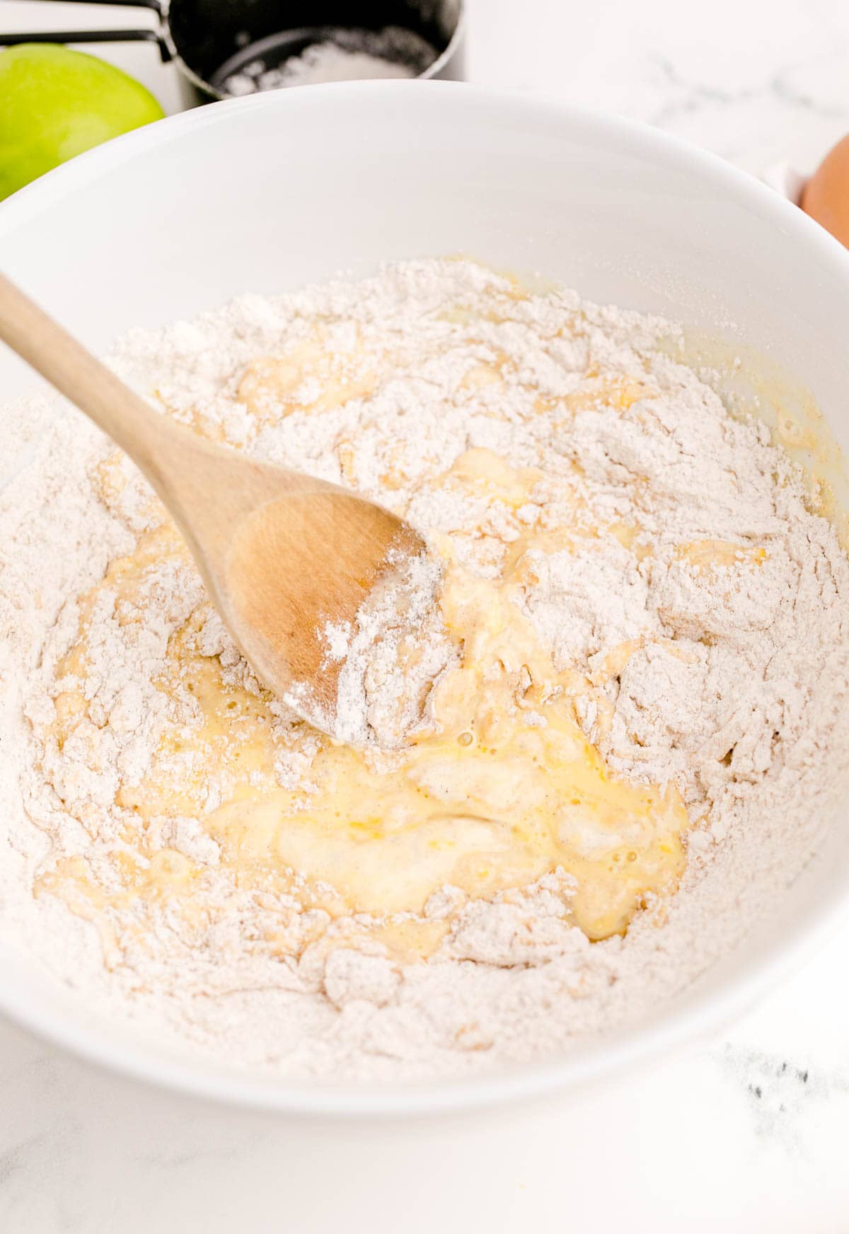 wet ingredients in a bowl of dry ingredients being mixed with a wooden spoon