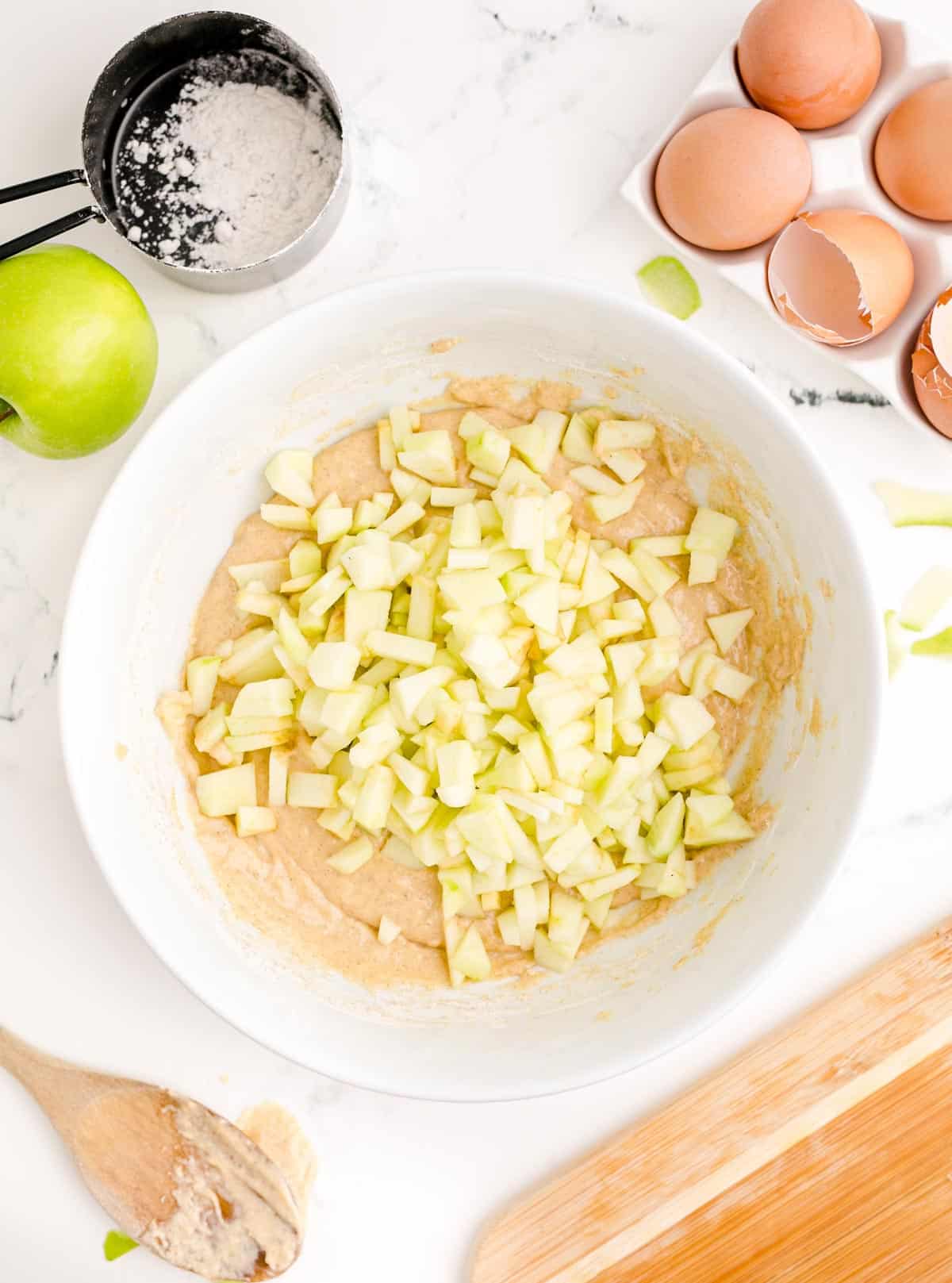 cut up apples in a white bowl with batter