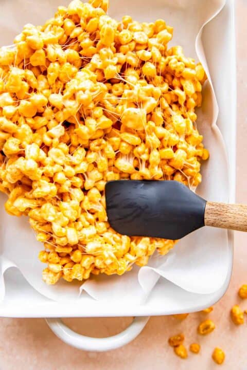 Cereal bar mixture is being pressed down into a casserole dish.