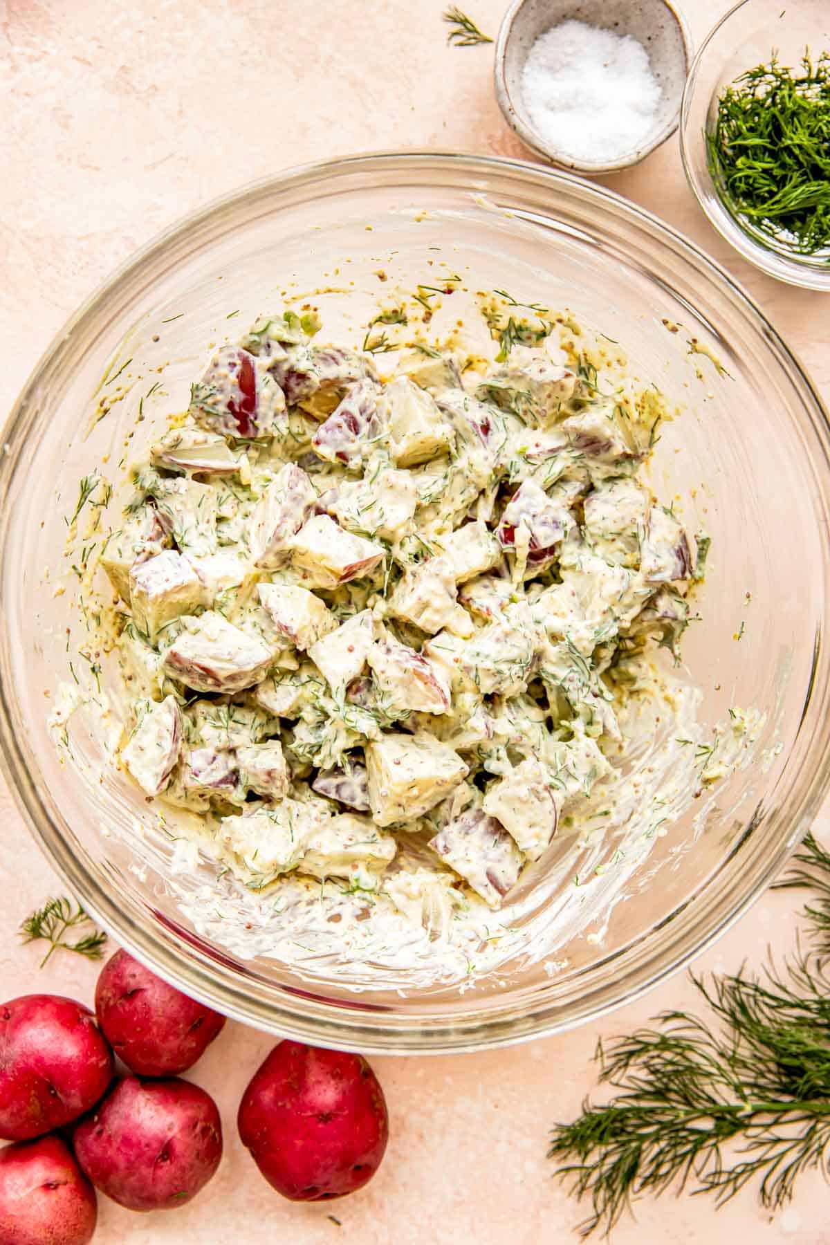 Potato salad is mixed together in a glass bowl. 