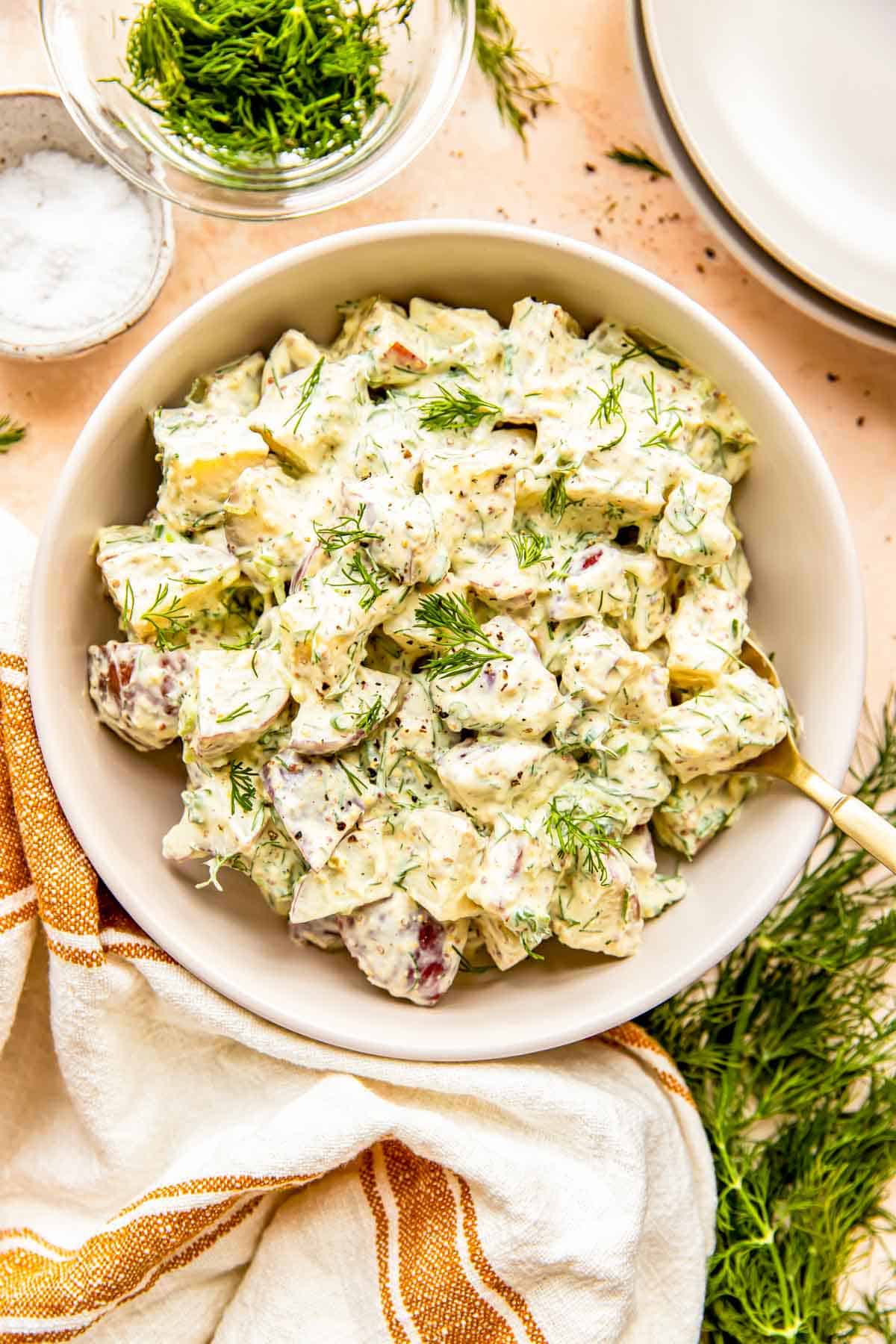 A large bowl is filled with dill potato salad. 