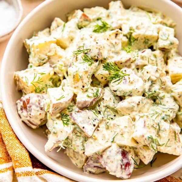 Fresh dill is sprinkled across the top of a potato salad.
