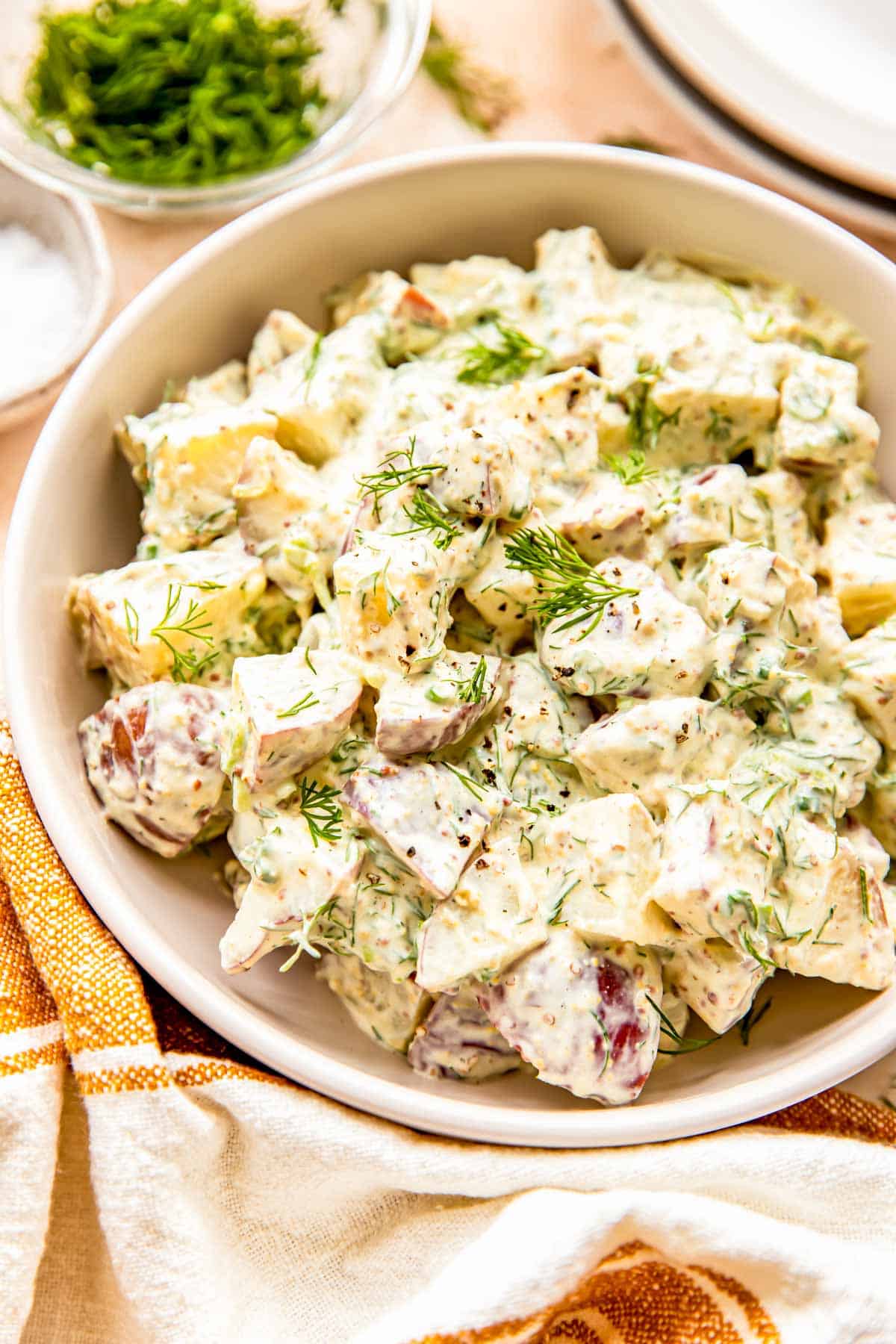 Fresh dill is sprinkled across the top of a potato salad. 