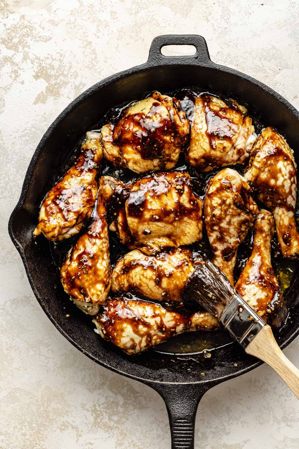 chicken is being glazed in a skillet