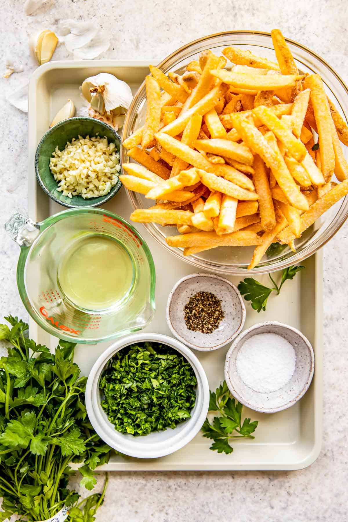 The ingredients for garlic fries are placed on a baking sheet. 