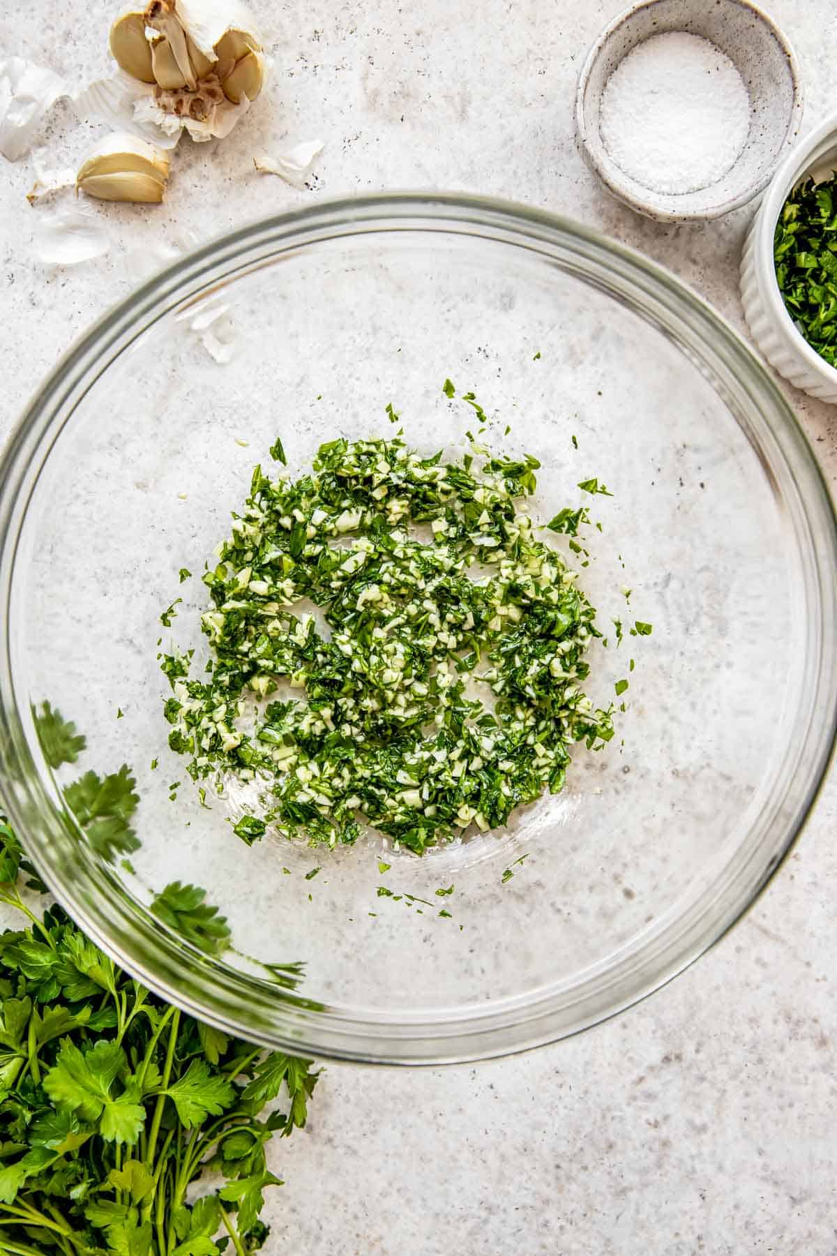 Garlic, parsley and oil are mixed together in a bowl.