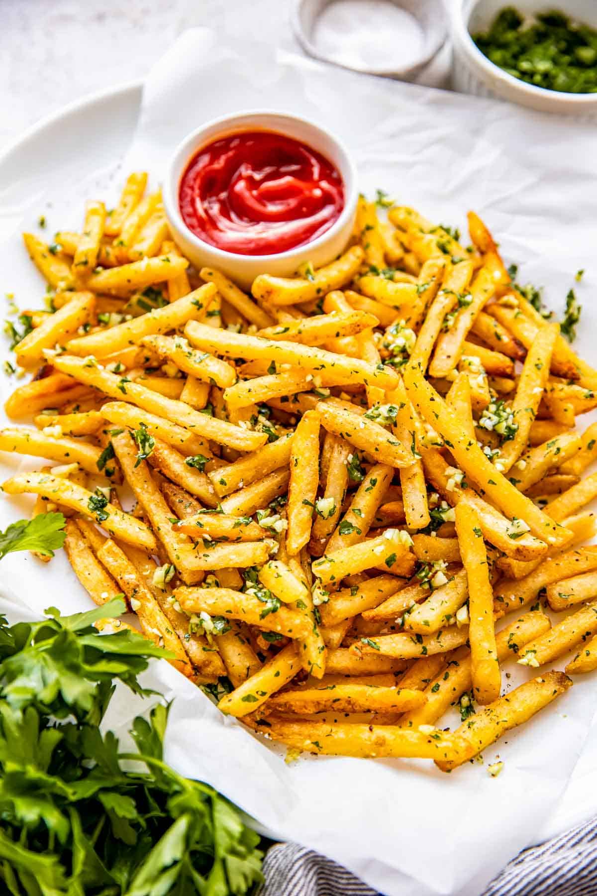 A small bowl of ketchup is placed on a tray filled with fries. 