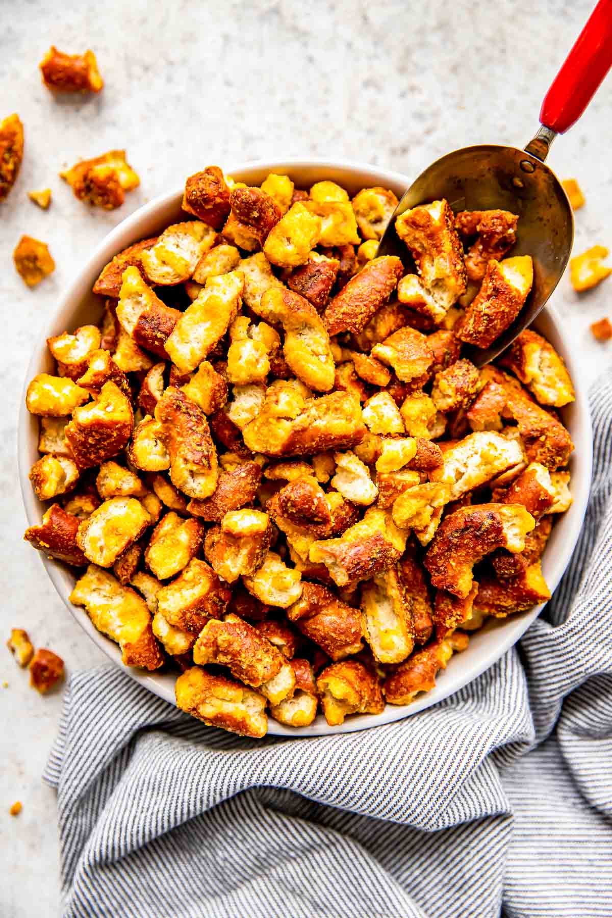 A scoop is placed in a bowl of honey mustard pretzels.