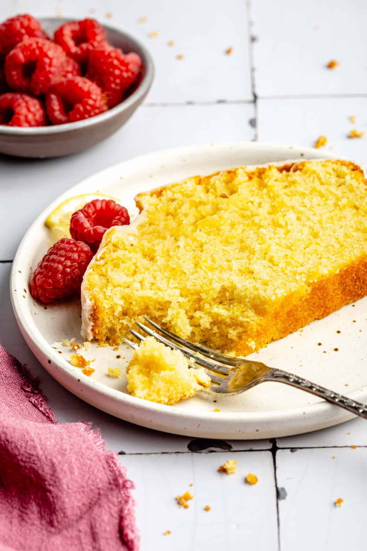 A fork has been placed on a plate with a single slice of lemon pound cake.