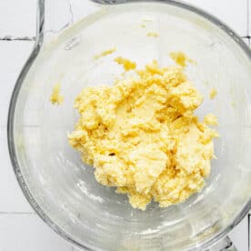 A butter mixture is in a glass mixing bowl.