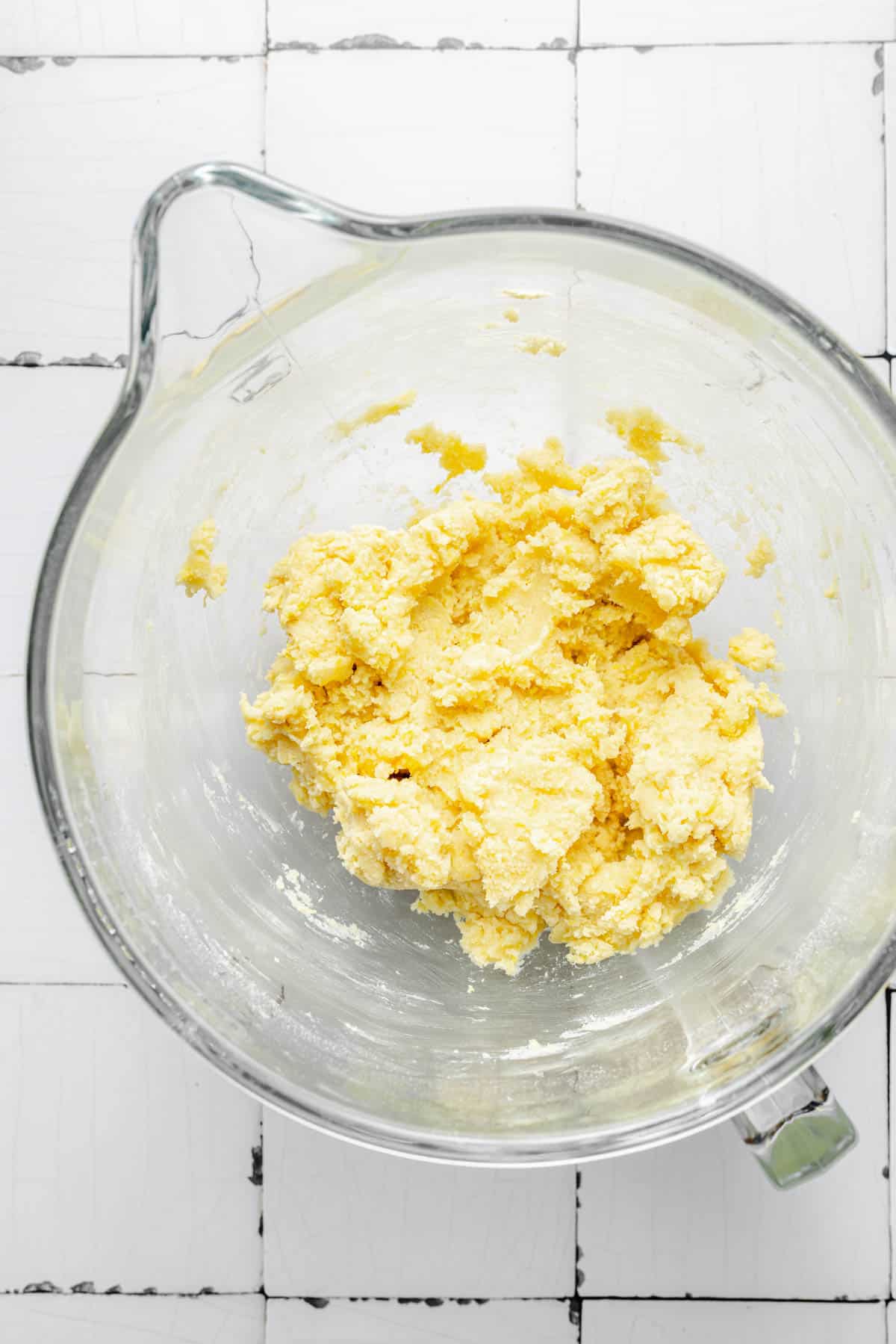 A butter mixture is in a glass mixing bowl.