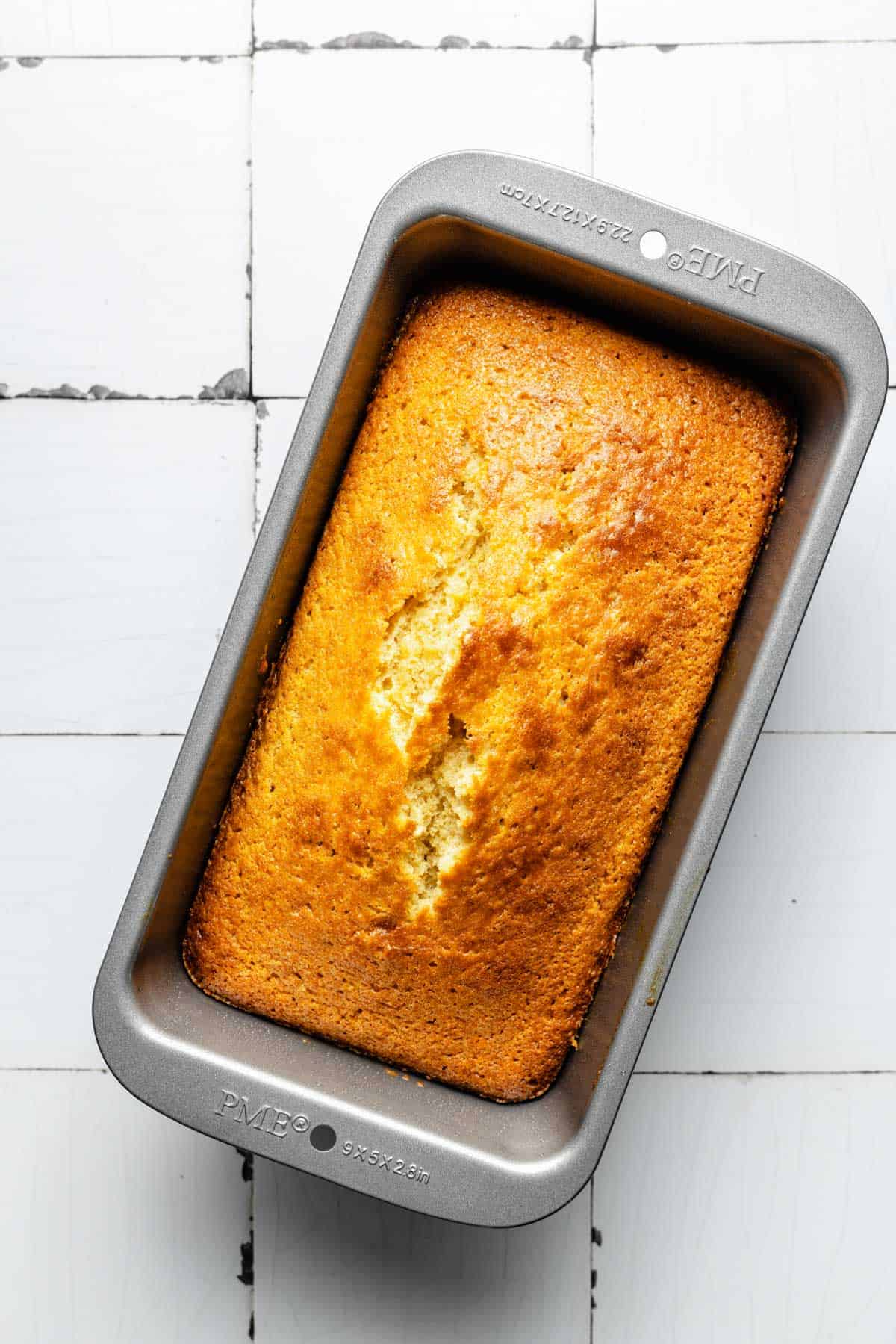 A baked pound cake is presented in a loaf pan.