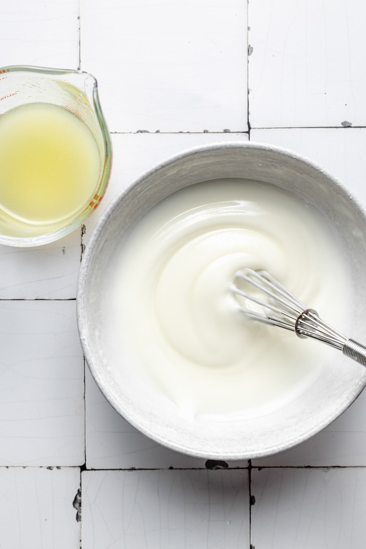 Icing is being whisked in a white bowl.