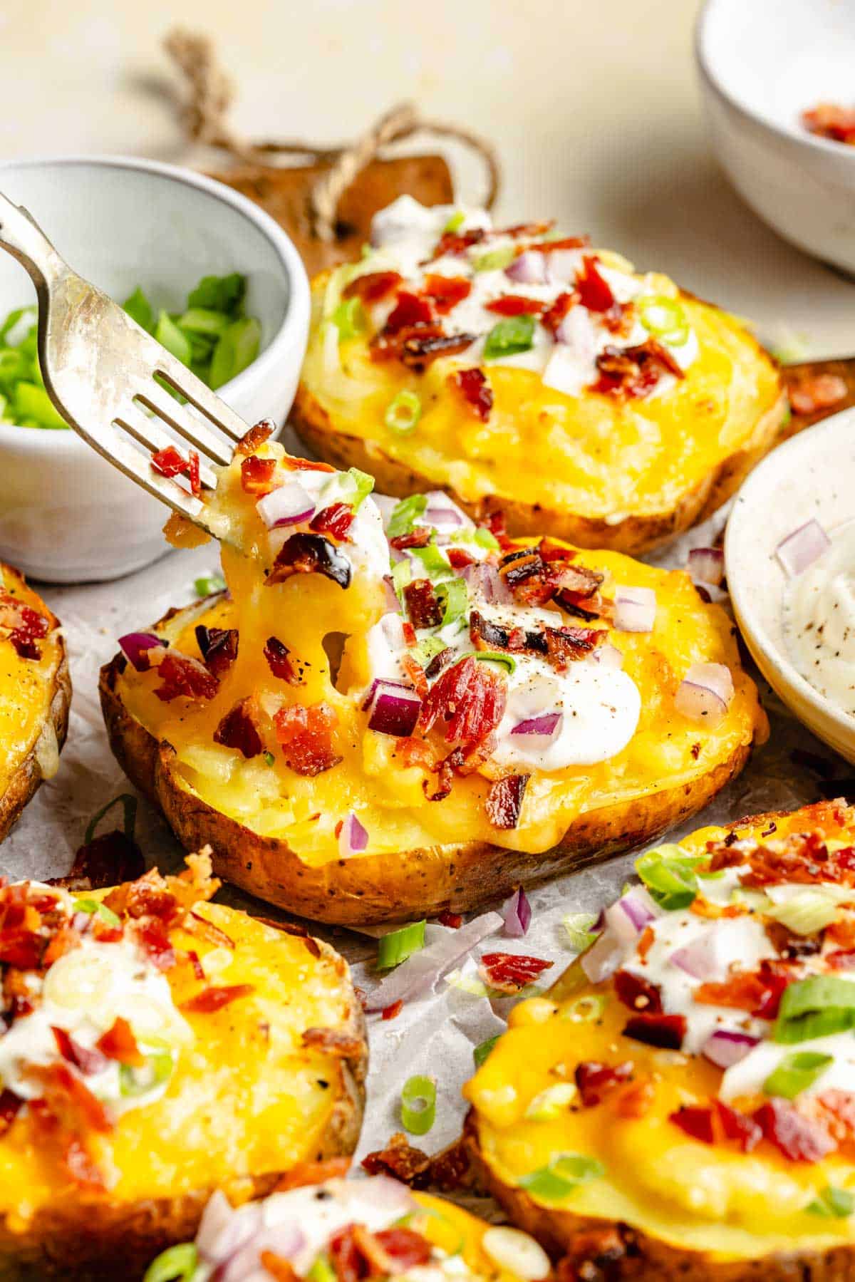 a fork is lifting a bite sized piece of potato from the twice baked potato