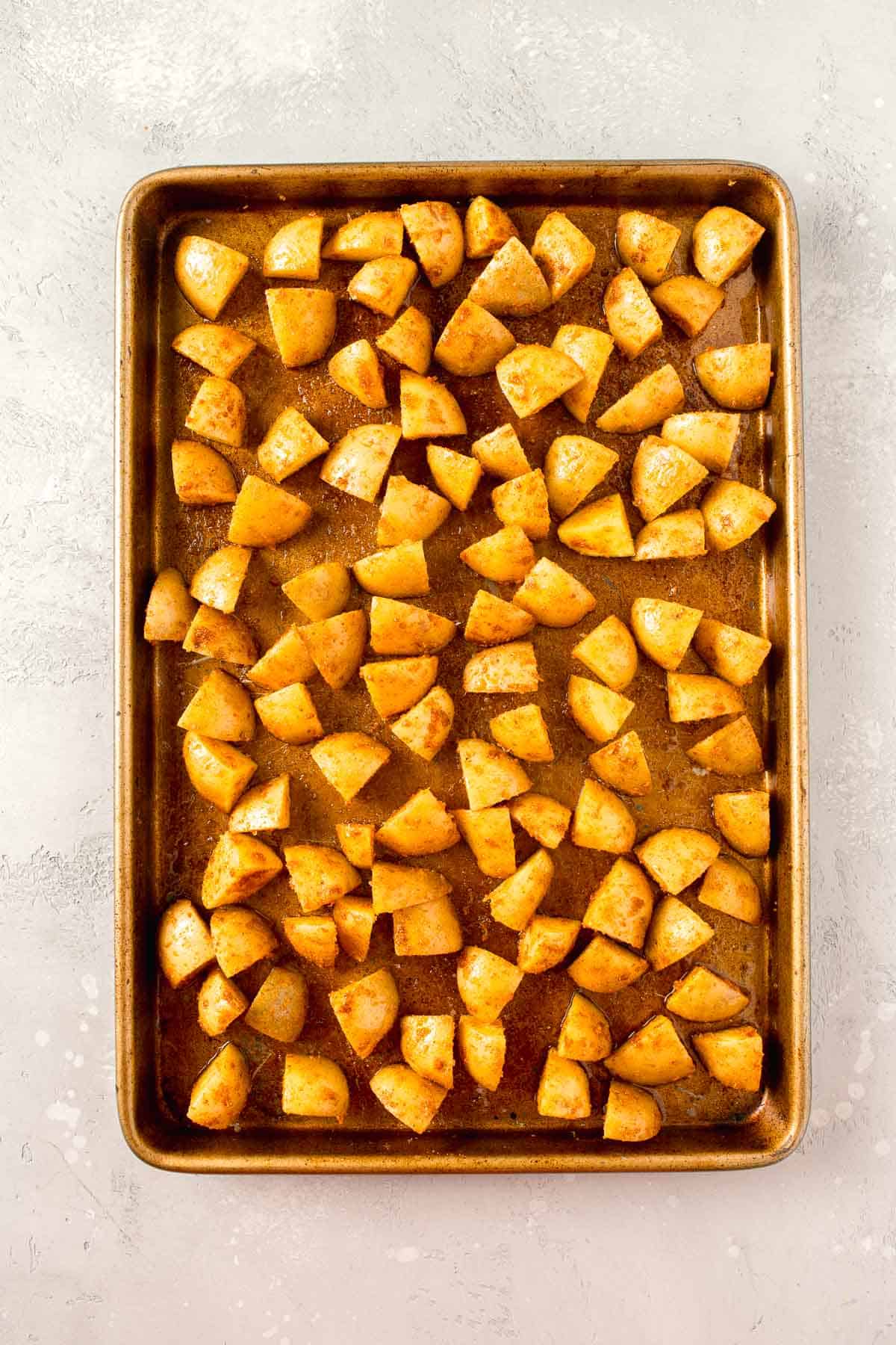 seasoned parmesan potatoes on a rimmed metal baking sheet
