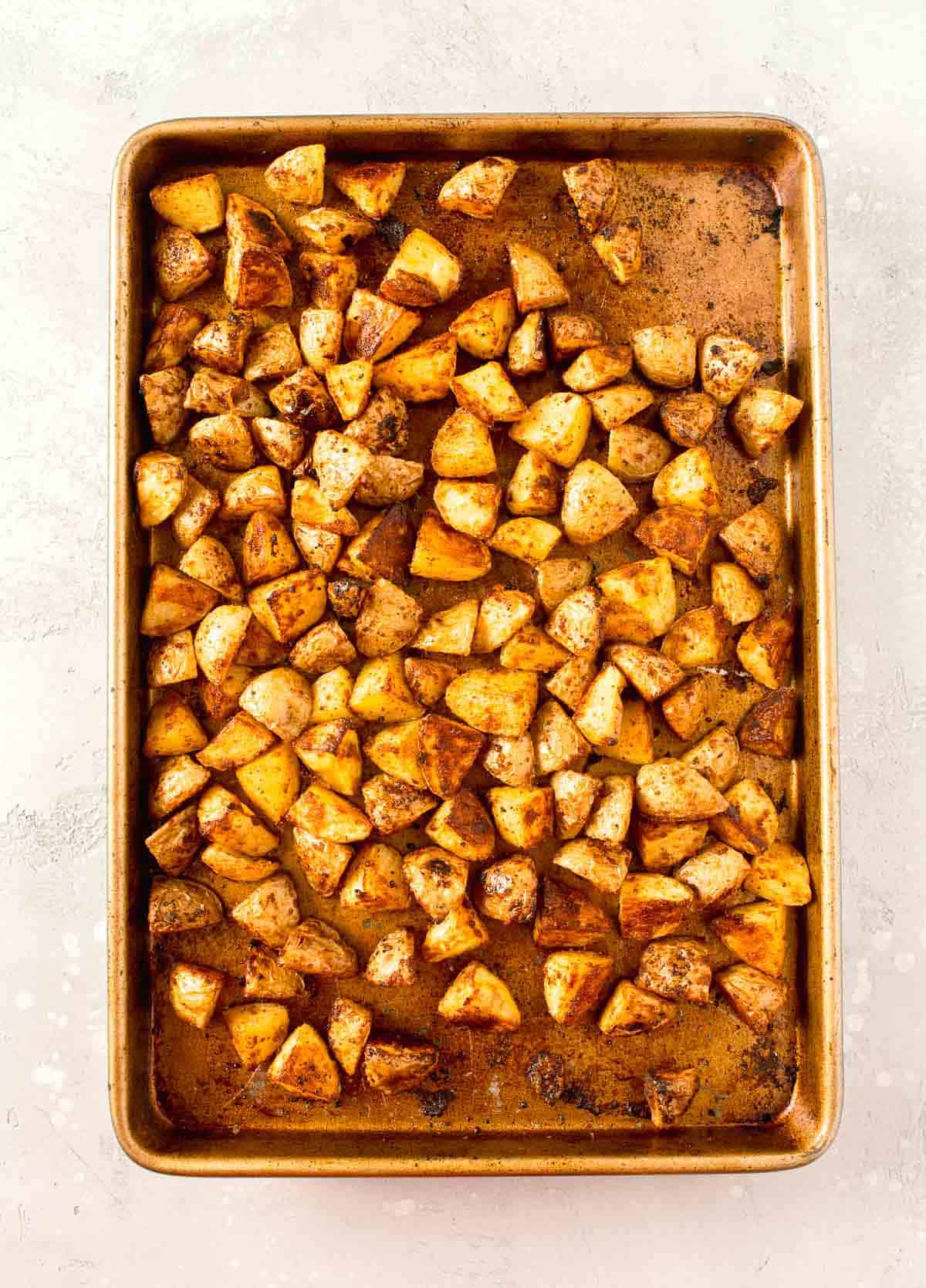 roasted parmesan potatoes on a rimmed metal baking sheet