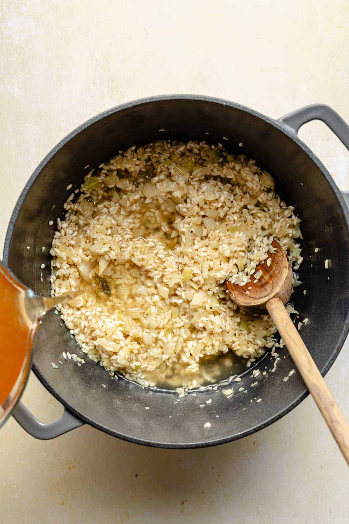 Adding chicken broth to risotto.