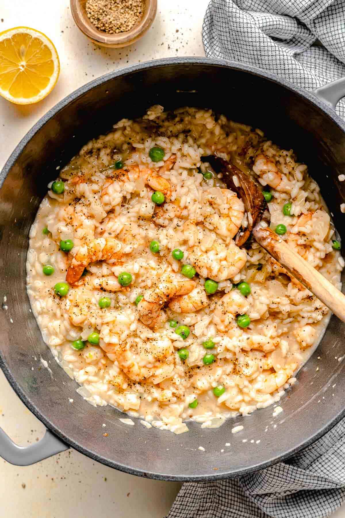 Shrimp risotto in a pot with a wooden spoon.