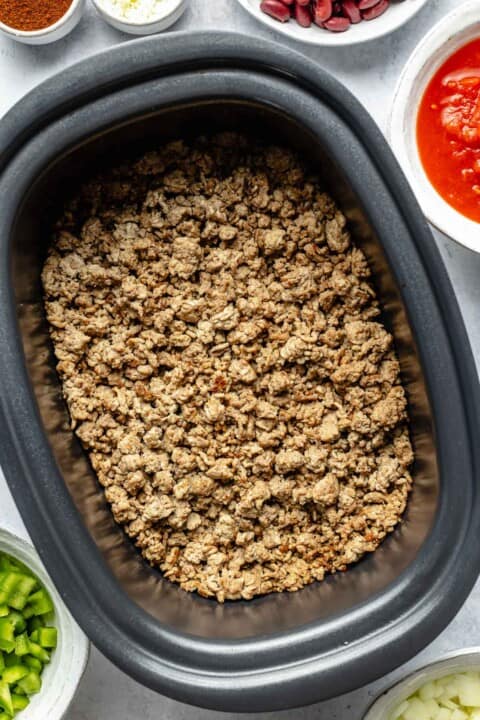 Adding browned meat to a crockpot.