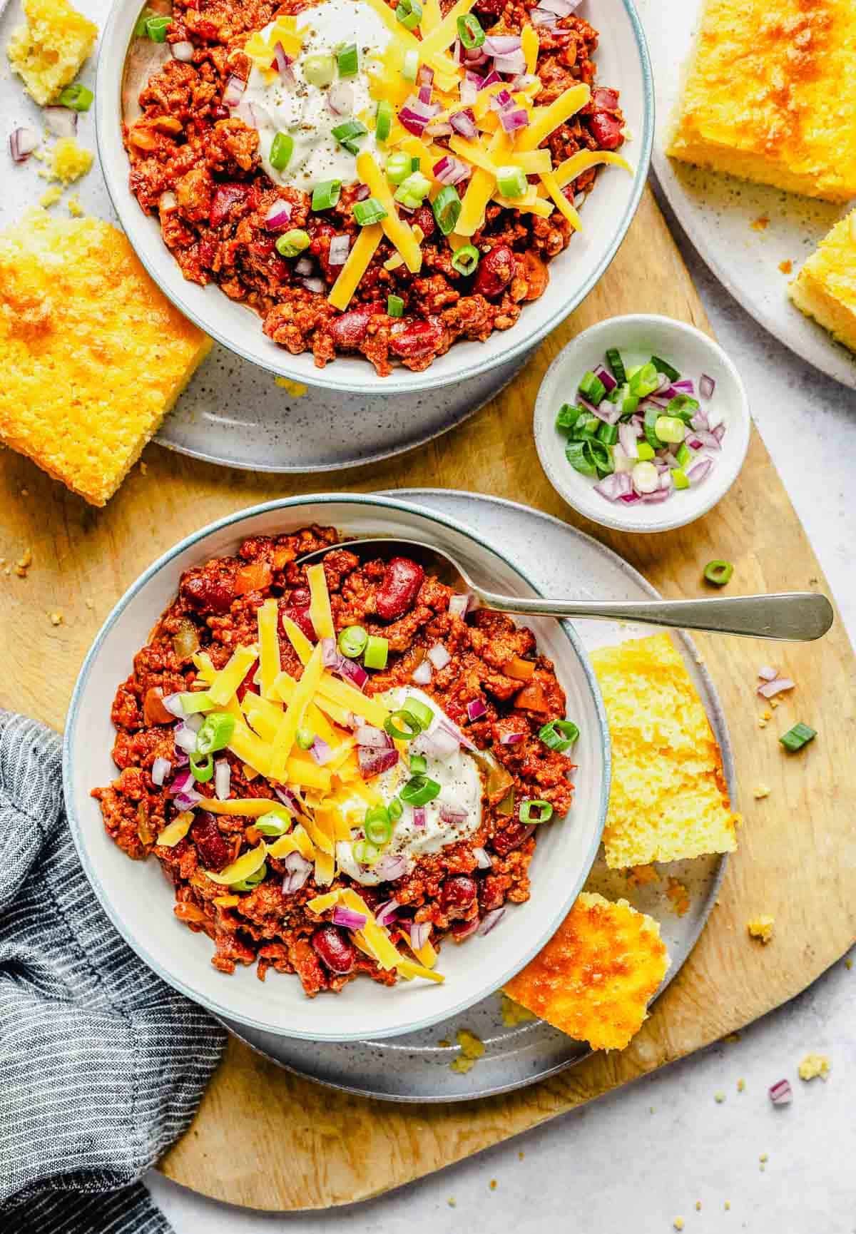 Overhead image of 2 bowls of slow cooker chili loaded with toppings.