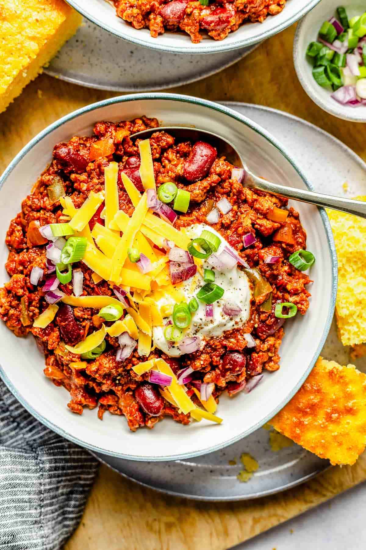 Overhead image of a bowl of slow cooker chili loaded with toppings.