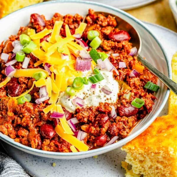 A bowl of slow cooker chili loaded with toppings.