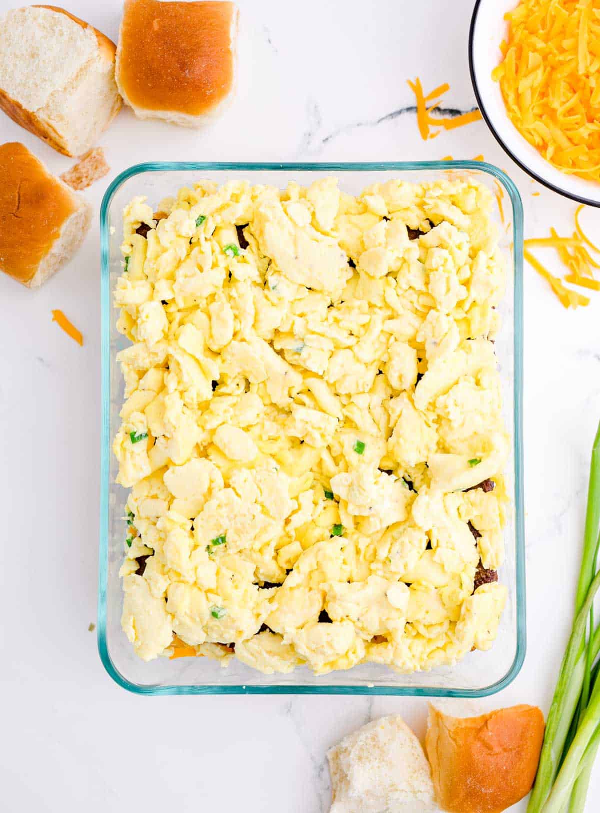 scrambled eggs added on top of sausage in a glass baking dish