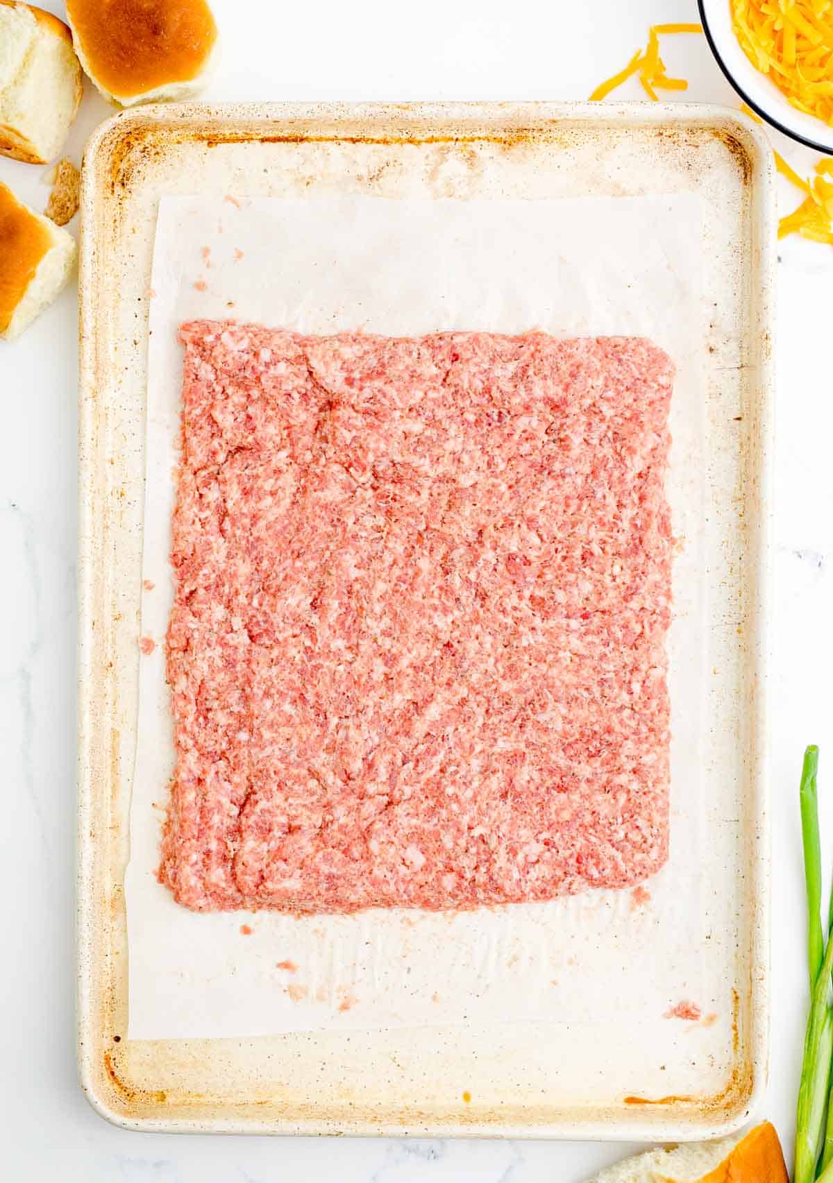 pork sausage pressed out into a square on a metal baking sheet lined with parchment paper