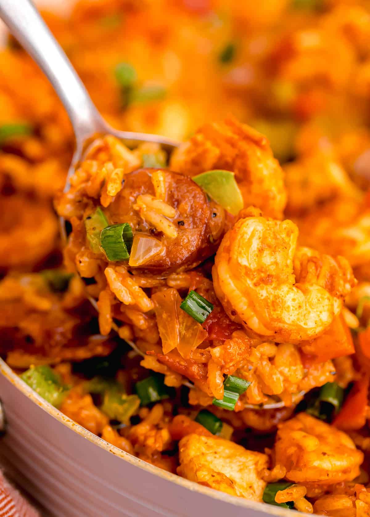 a spoonful of jambalaya being scooped out of a skillet