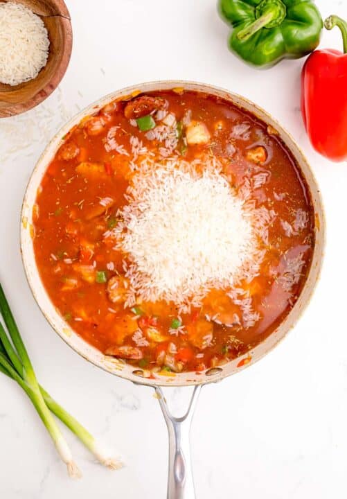 white rice added to the jambalaya mixture in the skillet