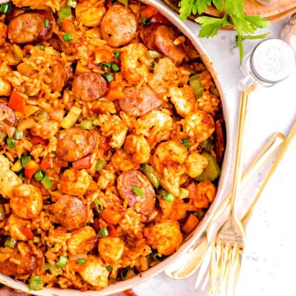 chicken and sausage jambalaya in a skillet next to gold utensils and a red linen towel